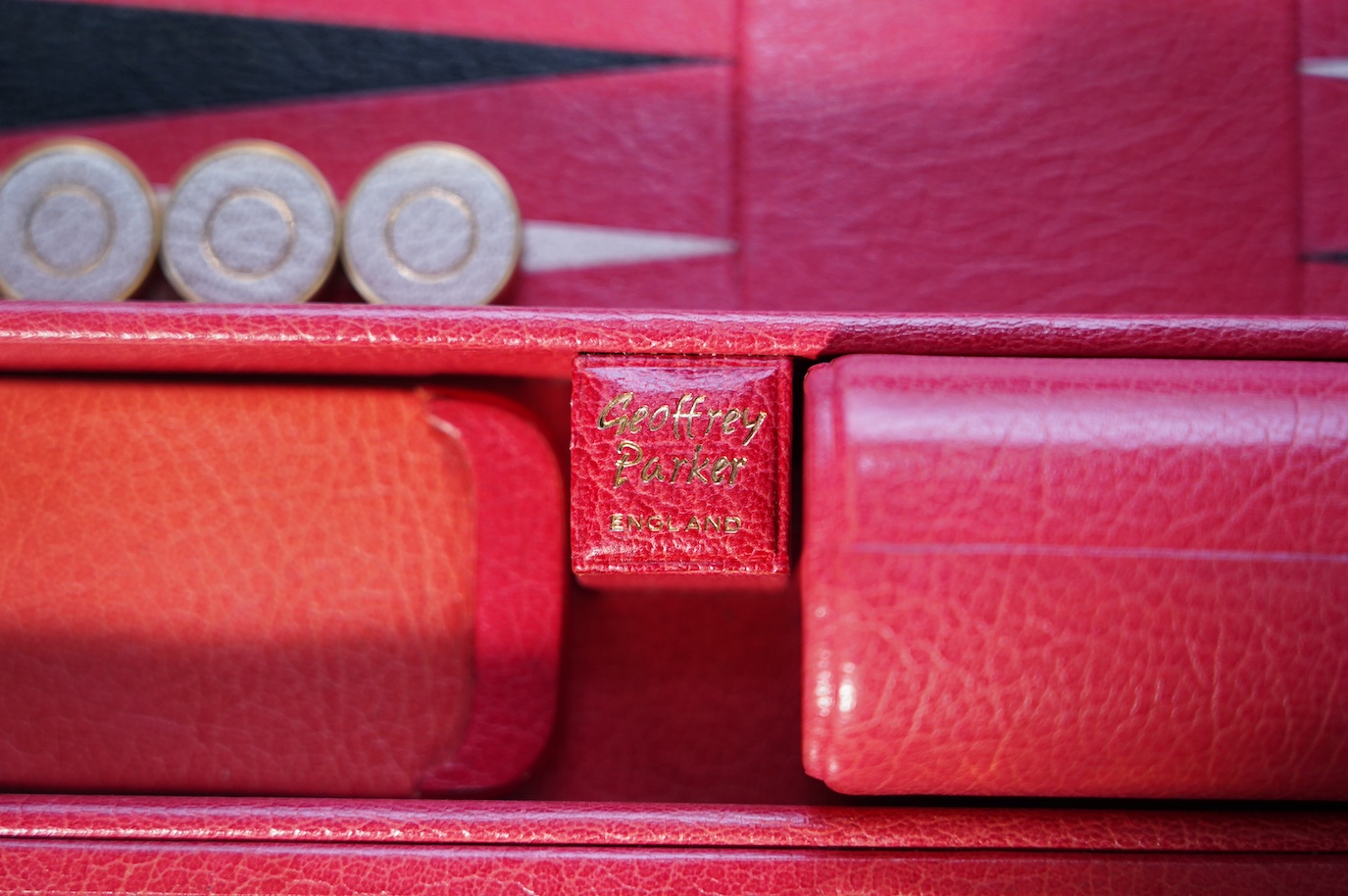 A Geoffrey Parker red leather backgammon set and a black leatherette wrist watch case